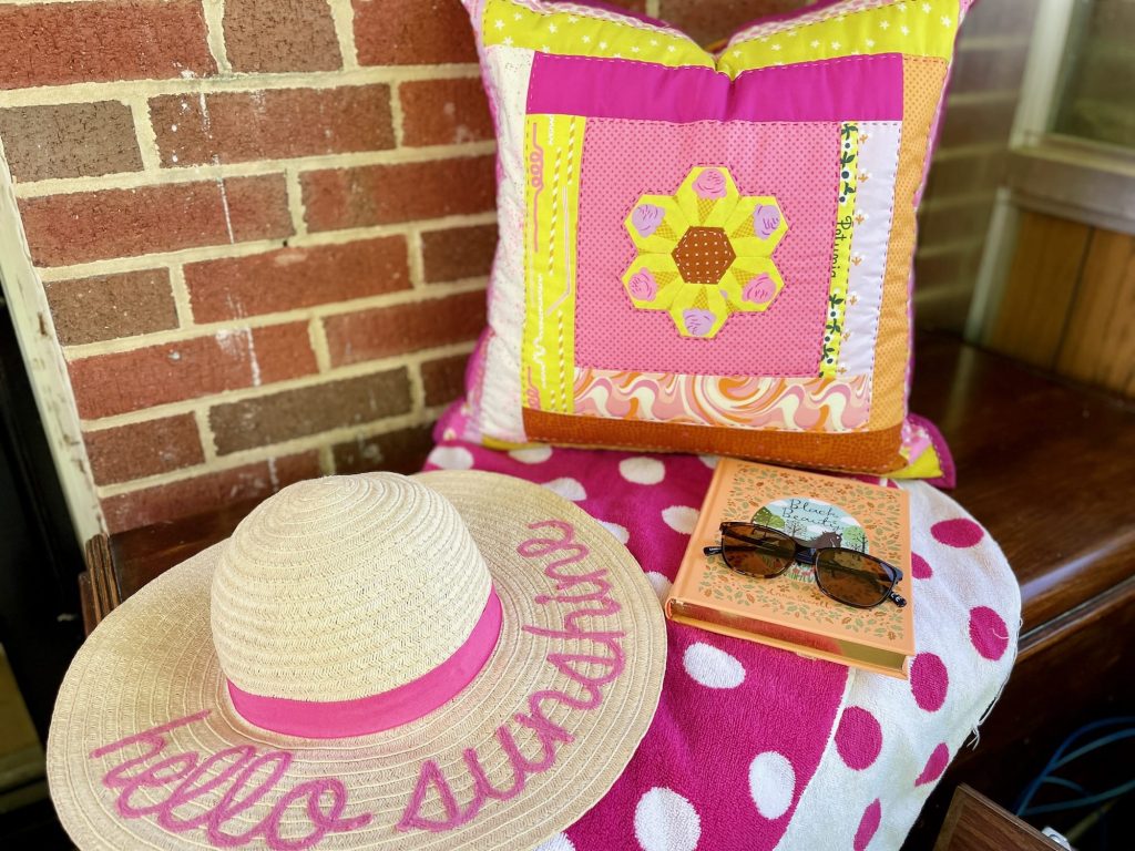 summer home pillow with straw hat sunglasses and book